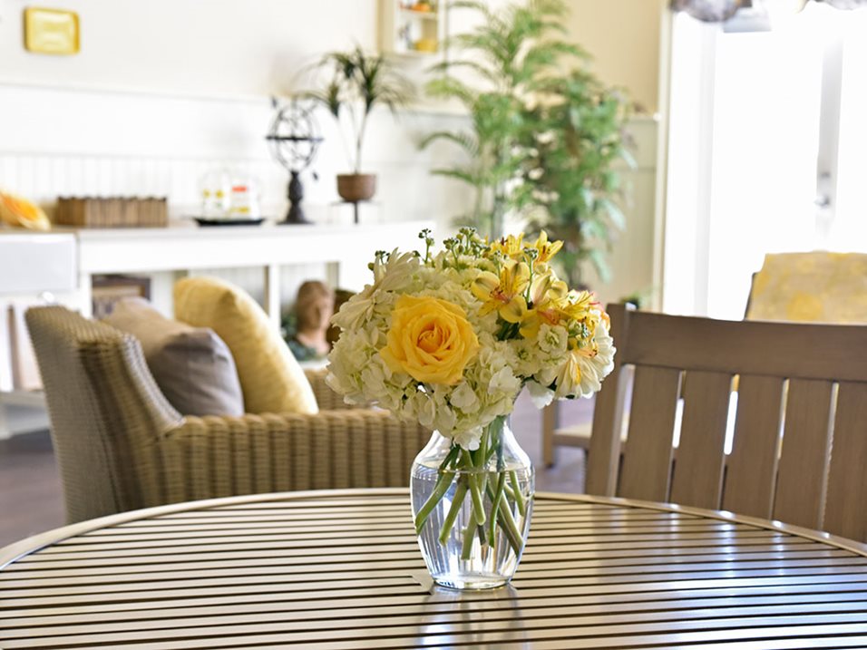 yellow flowers in a vase on a wooden table