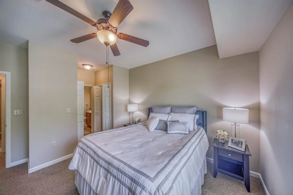 Bedroom with ceiling fan, bedside table, closet and bathroom