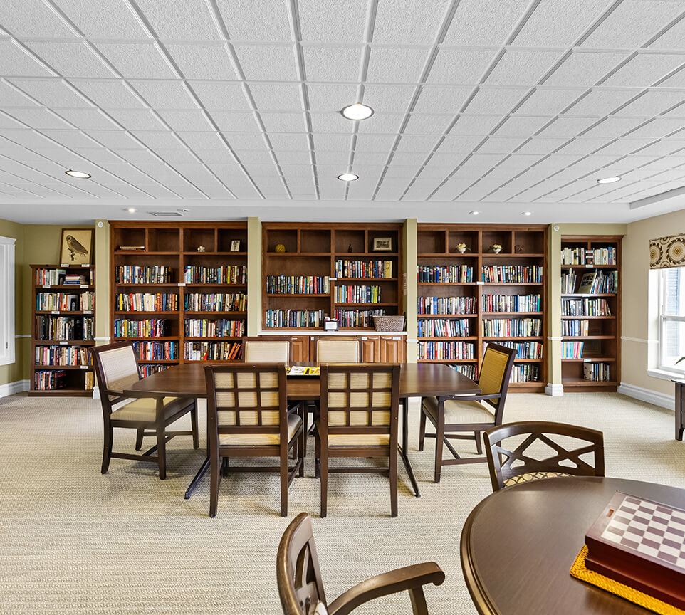 Library room with bookshelves and wooden tables in community building.