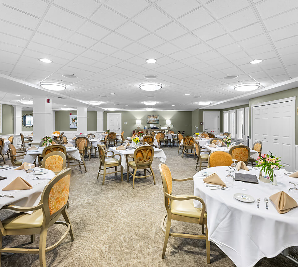 Bright dining area with tables set for a meal in a senior living community.