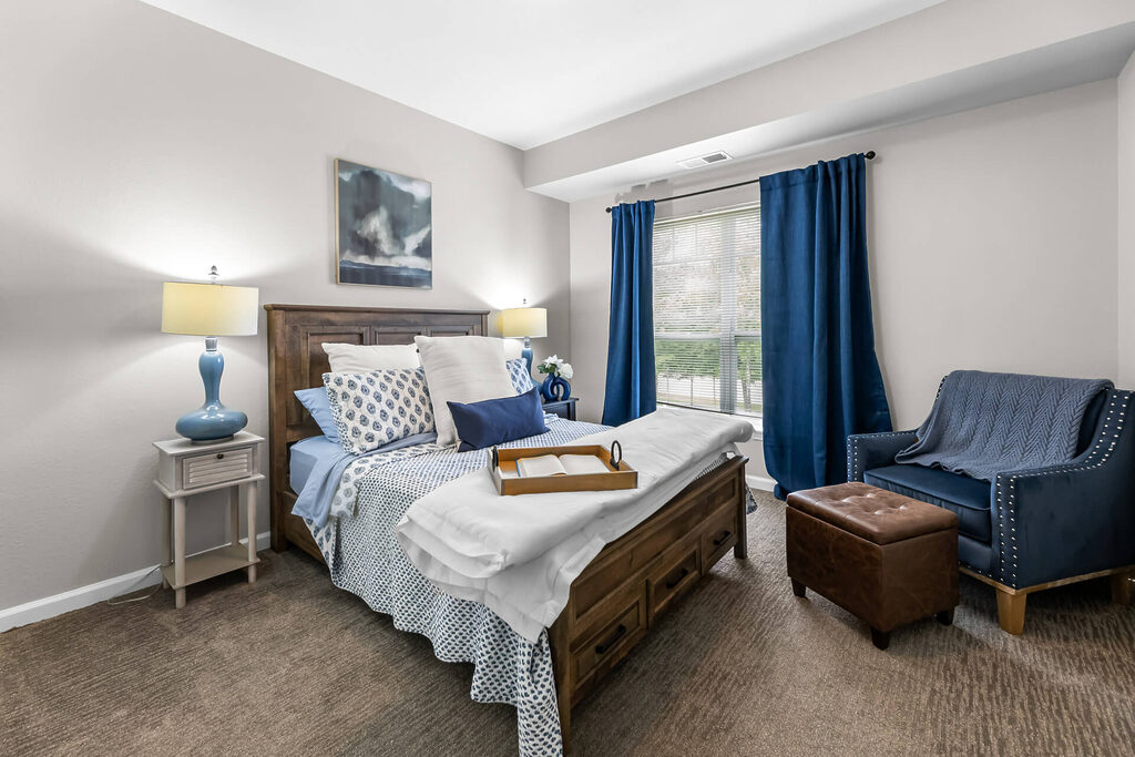 Cozy bedroom with blue accents and natural light from large window.